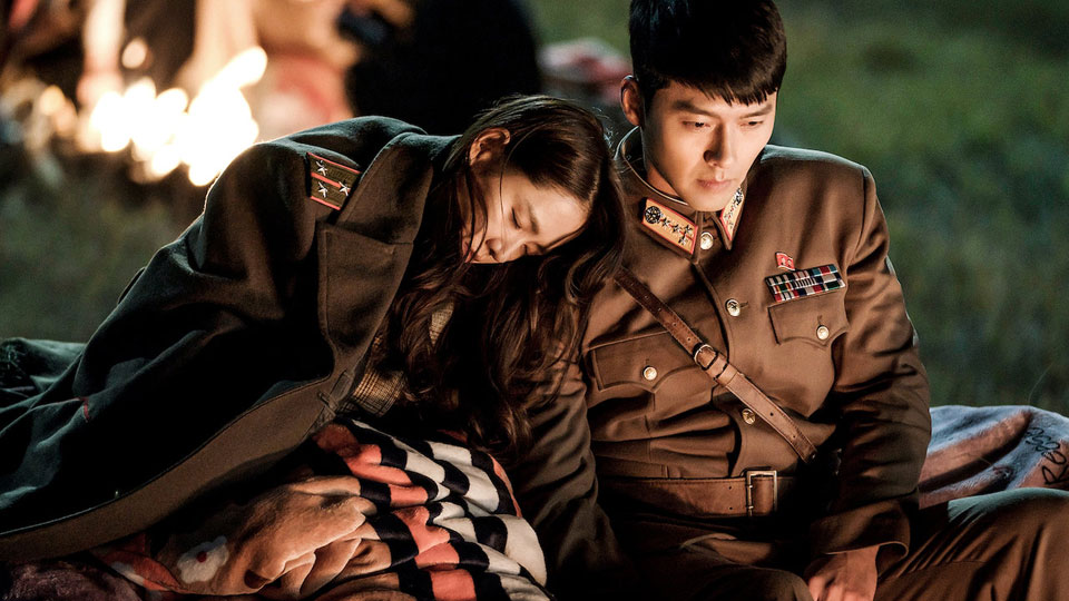 Crash Landing on You Captain Ri and Se-ri sitting by the fire as Se-ri sleeps on his shoulder